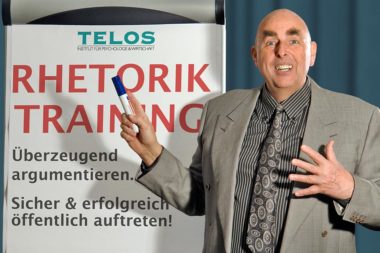 Referenten Dr. Elmar Teutsch Vortrag Rhetorik Flipchart Anzug grau Hemd Krawatte Filzstift Hand gespreizt Schrift Rhetorik Training D06846gp4nn