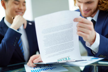 Verhandlung Vertrag Männer jung lächeln lesen Büro Klemmbrett / Fotobearbeitung: TELOS - webfrei 2865