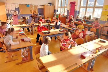 Schulende Klassenzimmer Kinder Jubel Freude lachen lärmen Lehrerin hält sich die Ohren zu / Foto: TELOS - C1812cG